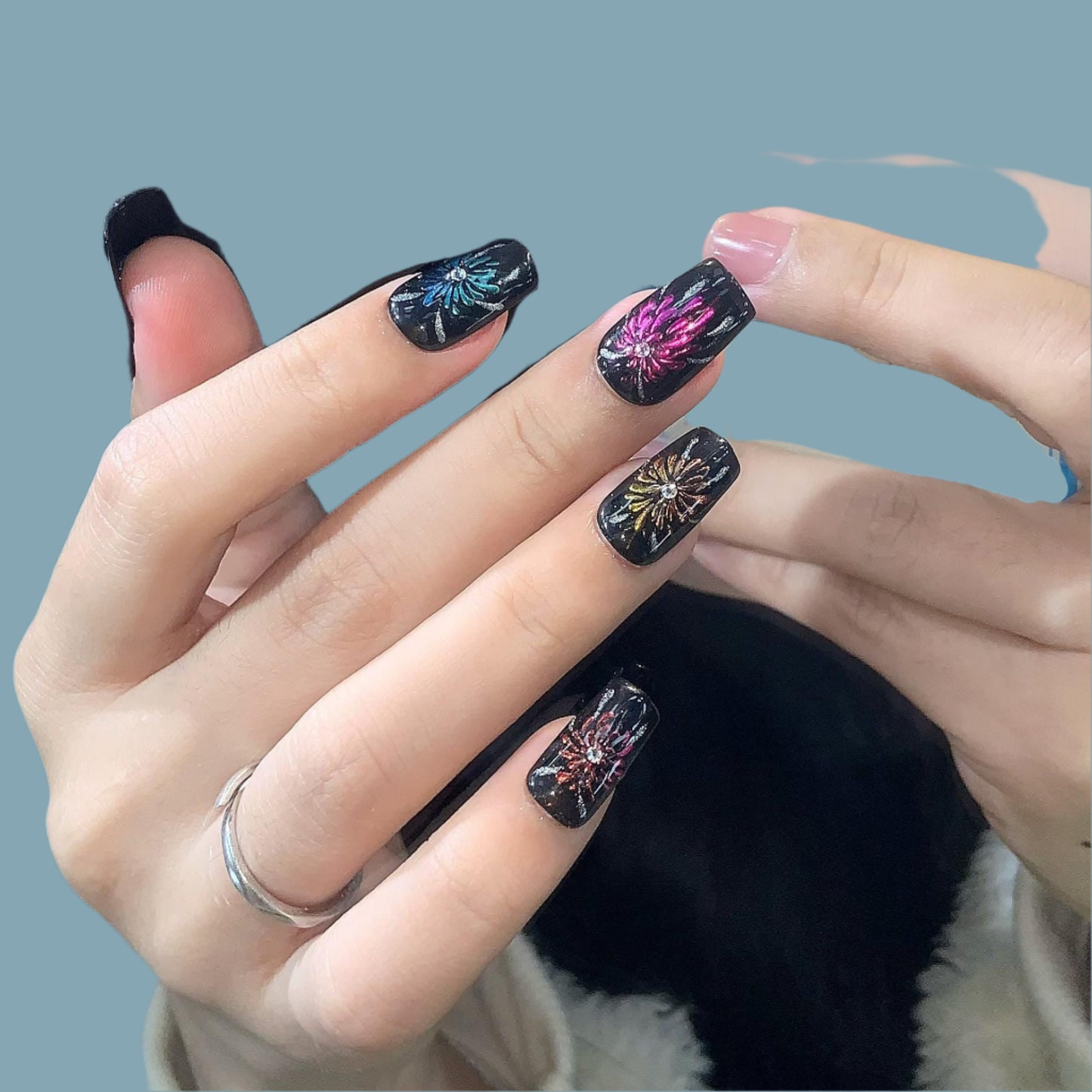 art, black base fireworks design, multicolo festive artificial nails, press-on glitter shiny accents colorful explosion, celebration theme.