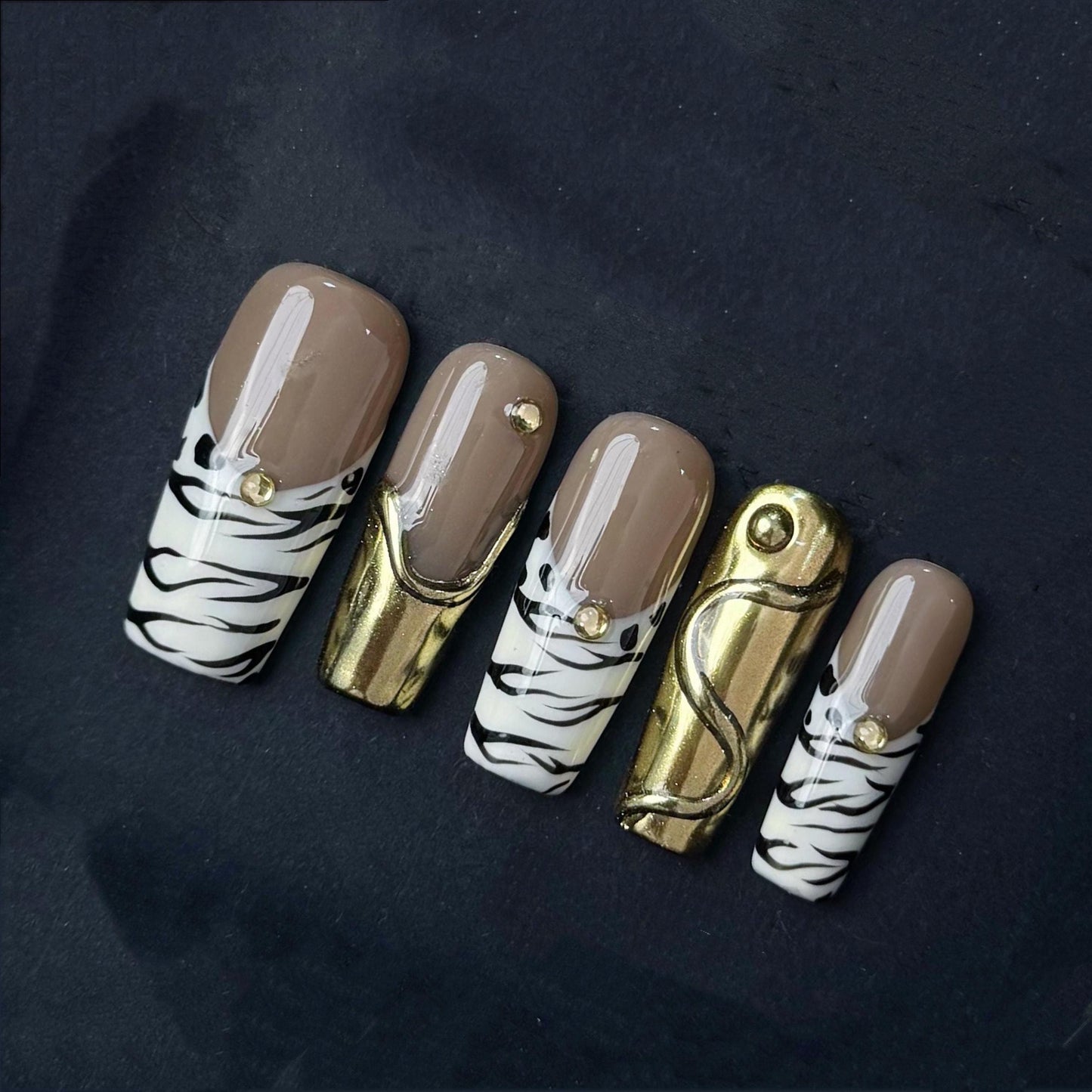 Gold Chrome and Zebra Stripe Press On Nails with Nude Base and Stud Accents. Artificial reusable fake glue on faux manicure nails trendy art