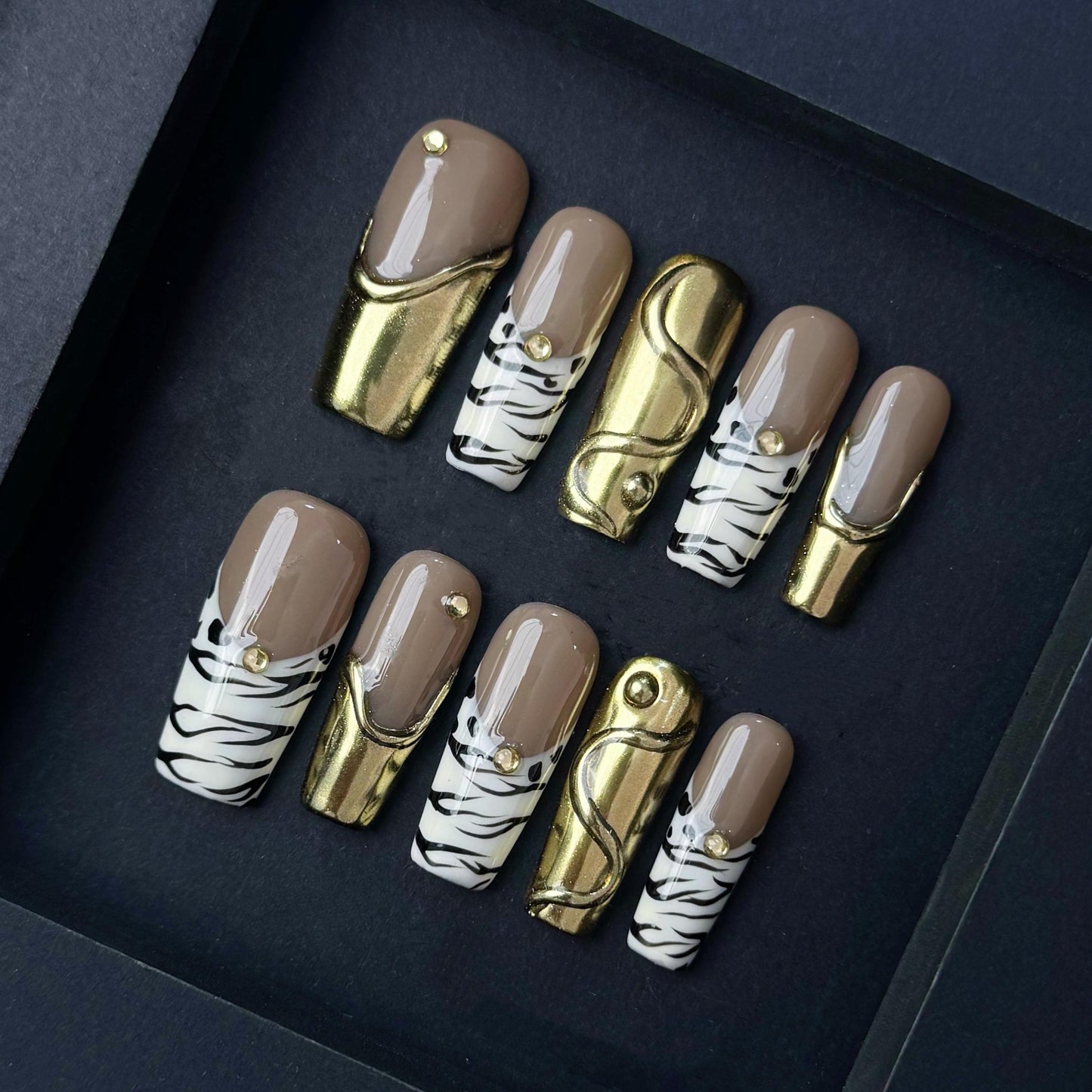 Gold Chrome and Zebra Stripe Press On Nails with Nude Base and Stud Accents. Artificial reusable fake glue on faux manicure nails trendy art