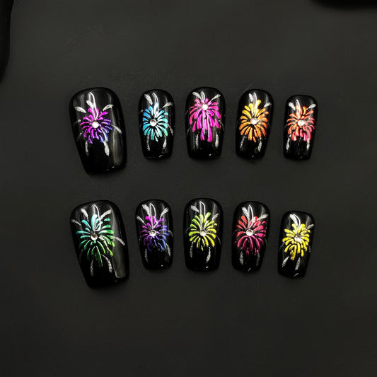 art, black base fireworks design, multicolo festive artificial nails, press-on glitter shiny accents colorful explosion, celebration theme.