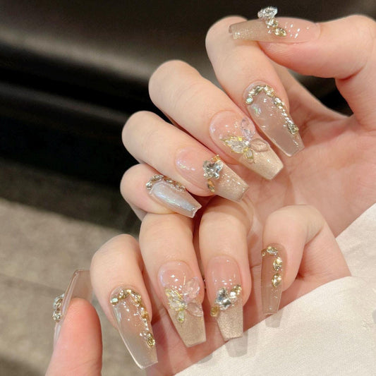 Champagne Glazed Nude Press-On Nails with 3D Butterfly and Gemstone Embellishments – Medium stiletto. Artificial reusable manicure nail art.
